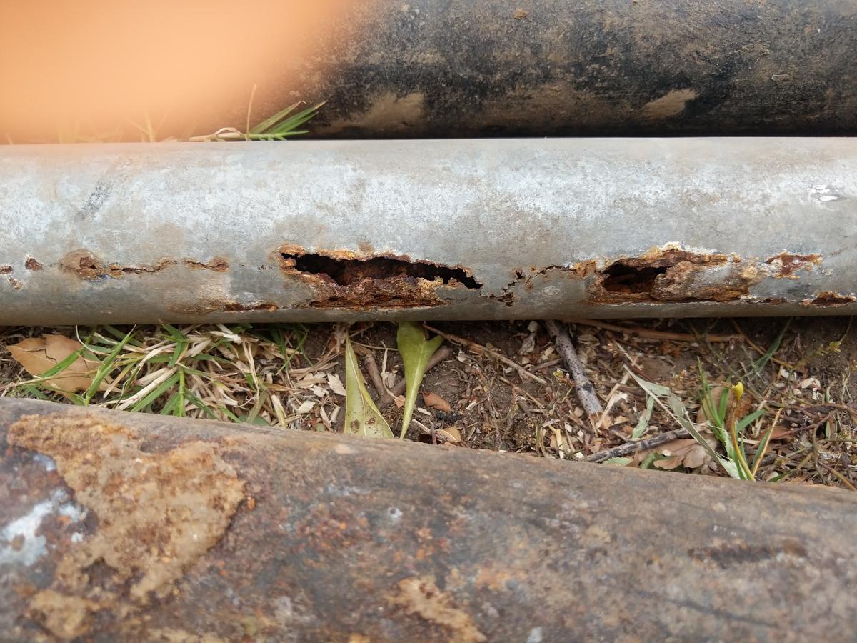 Corroded cast iron sewer pipe with holes eaten through the pipe wall