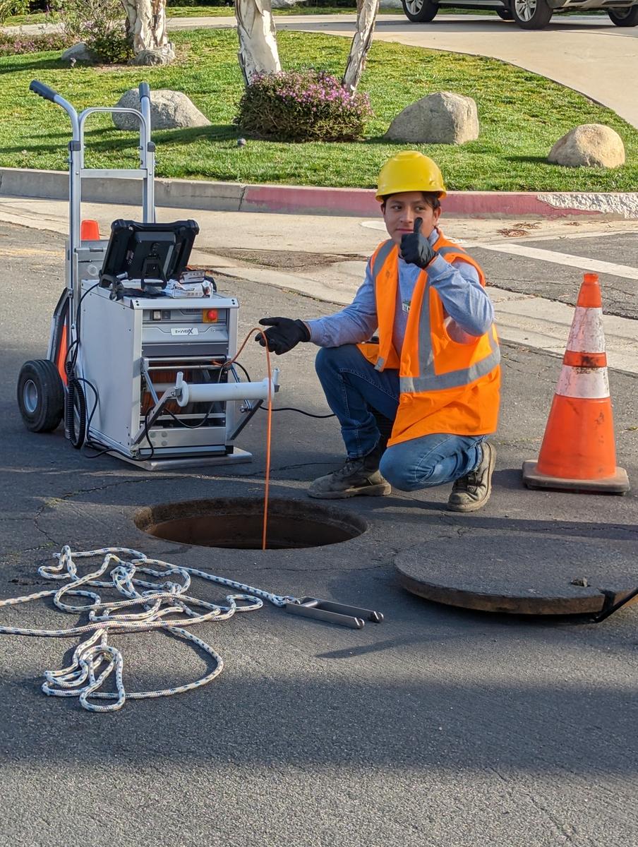 Technician running a sewer camera at an access point